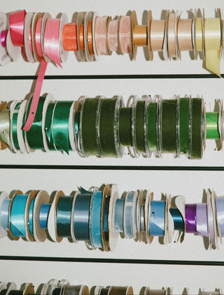 Rack with spools of colorful ribbon on a white background at Plum Social floral studio in Denver, Colorado