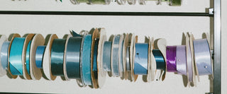 Rack with spools of colorful ribbon on a white background at Plum Social floral studio in Denver, Colorado.