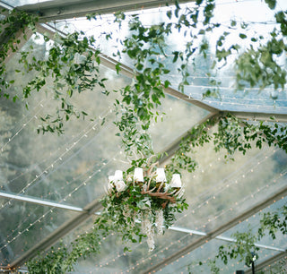 Chandelier hanging from a clear roof with greenery and string lights Aspen, Colorado wedding