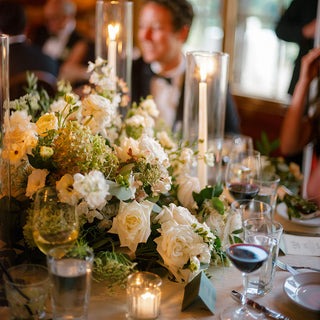 Elegant table setting with floral centerpiece, wine glasses, and candles.