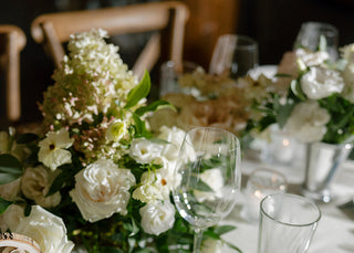Elegant table setting at a wedding in Pine Creek Cookhouse in Aspen, with floral arrangements, glasses, and cutlery on a white tablecloth.