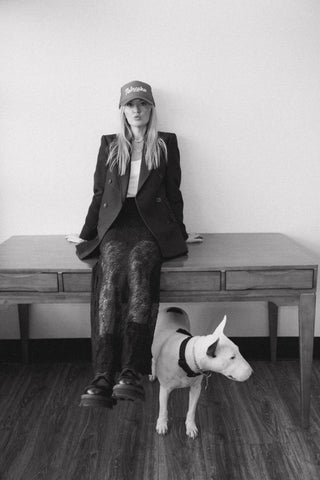 Owner of Plum Social flower studio sitting on a desk with a dog by her, in black and white.