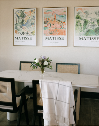 Consultation room with a table and chairs, featuring Matisse art prints on the wall, at Plum Social floral studio in Denver, Colorado.